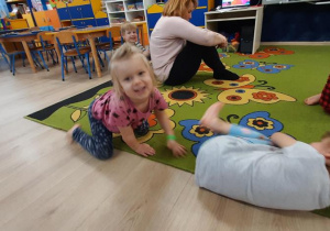 Zabawa "Kamień"- zdiewczynka próbuje przepchnąć kolezankę, siedzącągo na dywanie.