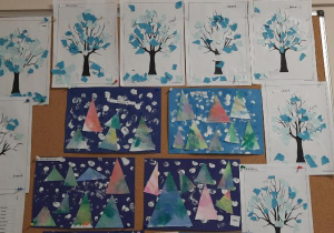 Wystawa prac na tablicy przedszkolnej - zimowa wydzieranka i choinki.