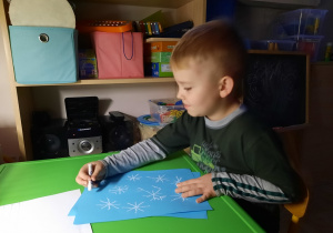 Chłopiec rysuje gwiazdki kredą.