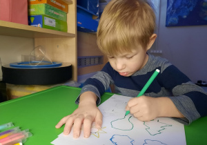 Chłopiec rysuje wory pisakiem po śladzie.