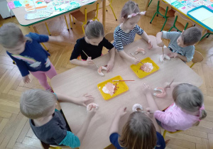 Dzieci malują rogaliki ulepione z masy solnej.