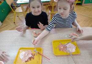 Dzieci malują rogaliki ulepione z masy solnej.