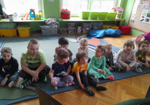 Dzieci siedzą na dywanie.
