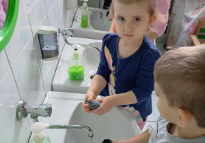 Dzieci piorą skarpety przy umywalkach.
