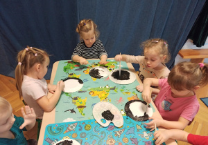 Dzieci maluja czarną farba talerzyki