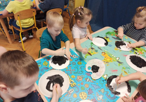 Dzieci maluja czarną farba talerzyki