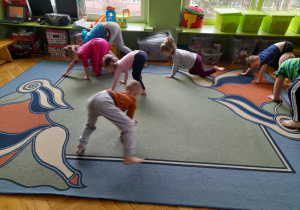 Dzieci ćwiczą na dywanie.
