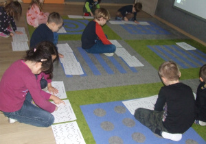 Dzieci odtwarzają rytm wodząc palcem po śladzie.