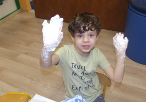 Chłopiec pokazuje ręce umoczone w masie.