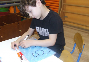 Chłopiec rysuje po folii bąbelkowej.