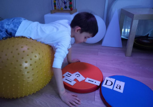Dziecko układa napis ćwicząc na piłce
