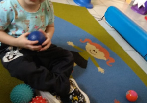 Chłopiec manipuluje sensorycznymi piłkami.