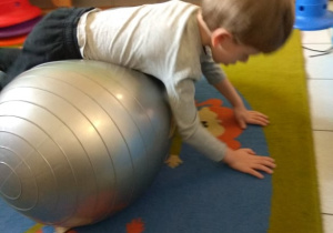 Chłopiec balansuje na dużej piłce.