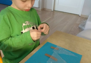 Chłopiec maluje farbami po folii bombelkowej.