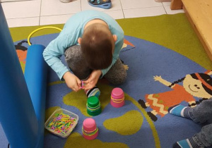 Chłopiec nakłada na kubeczki kolorowe gumki.