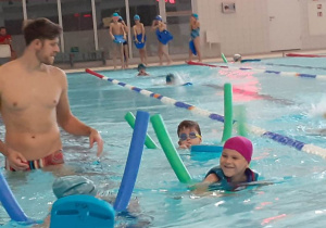 Dzieci pływają pod kierunkiem instruktora.